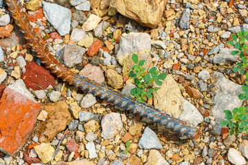 Old rusty metal fittings against a background of piles of stones and other construction debris. Construction background.