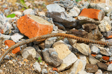 Old rusty metal fittings against a background of piles of stones and other construction debris. Construction background.