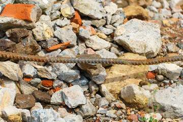 Old rusty metal fittings against a background of piles of stones and other construction debris. Construction background.
