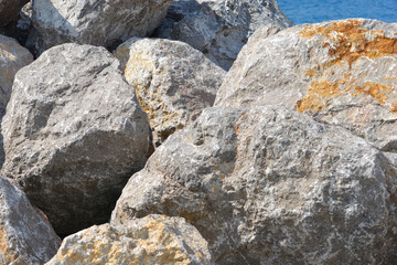 A close-up view of a pile of large, gray rocks next to a breakwater