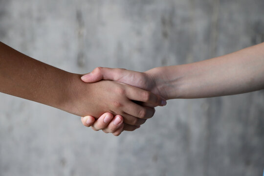 Children handshake on gray background. Two teenagers shaking hands in a gesture of agreement friendship.