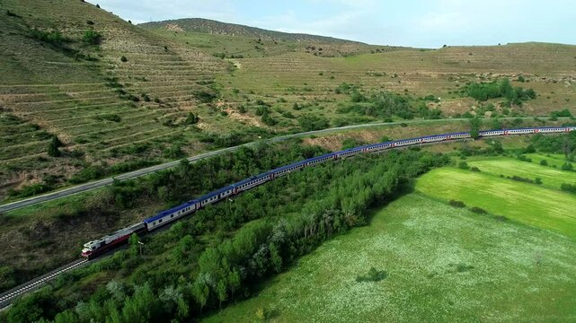 In spring, a narrow-gauge railway station in a small town hosts trains near the river.Trains run on tracks, carrying cargo or passengers, powered by locomotives or motors, unlike floating maglev train
