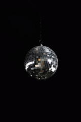 A high-angle perspective shot of a shiny mirrored disco ball against a wall in intense jet black, featuring copy space