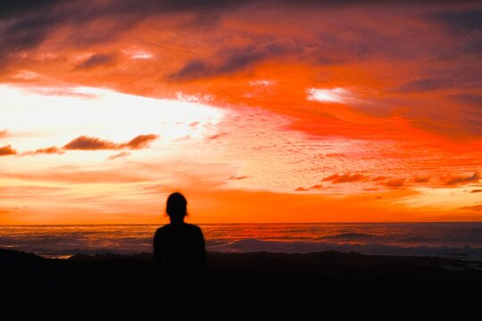 Silhouette of Woman Watching Dramatic Sunset Over Mountain Landscape