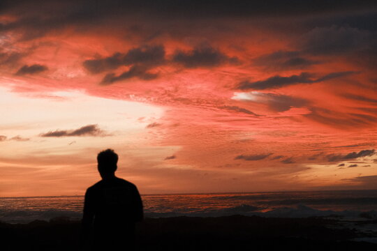 Silhouette of Woman Watching Dramatic Sunset Over Mountain Landscape