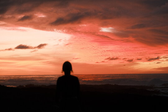 Silhouette of Woman Watching Dramatic Sunset Over Mountain Landscape