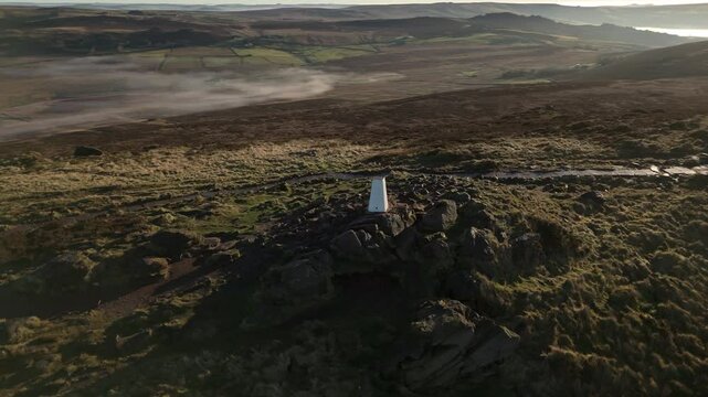 Fast aerial drone orbit reveal shot of The Roaches trigonometry point during a cloud inversion in the Peak District National Park, England, UK.
