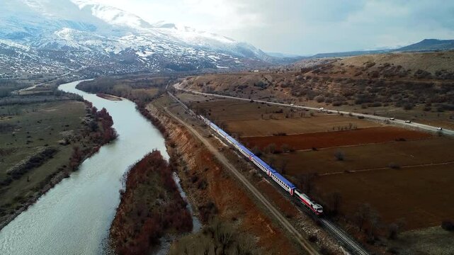  By the river, a narrow-gauge railway station in a small town. A train, powered by a locomotive or motors, runs along tracks, carrying passengers or cargo, unlike maglev trains that float.