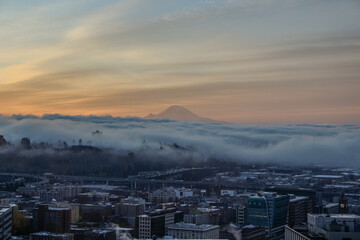 Seattle sunrise with Mt Rainier in the background and fog rolling over the city