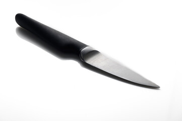 Sharp kitchen knife rests elegantly on a reflective surface in bright lighting