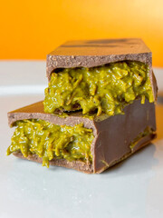 On an orange background, pieces of Dubai chocolate lie on a plate