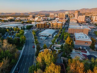High-angle view of a city street scene with cars, buildings, and a park. Urban landscape with mountains in the background. Downtown, Boise, Idaho, USA.