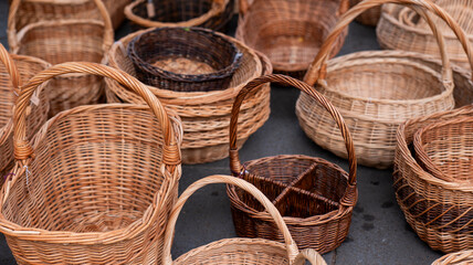 A collection of handcrafted wicker baskets in various shapes and sizes displayed on a flat surface. The natural textures highlight traditional craftsmanship.