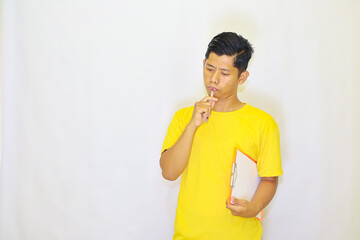 A Young Man in Yellow, Contemplating with a Pen and Clipboard, Deep in Thought or Decision-Making...