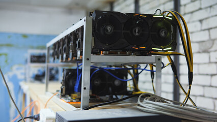 Close-up shot of graphic cards mining cryptocurrency on a rig, showing cables against a blurred background. Highlighting digital currency tech