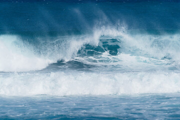 Large powerful wave in blue ocean.