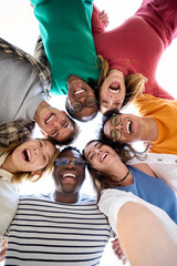Vertical. Selfie from below of diverse group friends posing embracing in circle looking excited at...