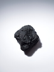 Dark grey coal lump on isolated white surface, white surface, inanimate object, isolated