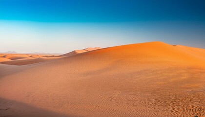 Vast expanse of orange sand dunes under a clear blue sky.