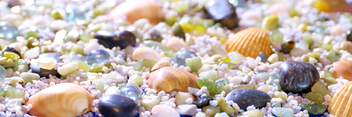A vibrant collection of seashells and smooth stones scattered over white sand, capturing the beauty of natural beach treasures in a colorful, lively setting.