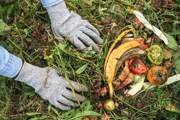 Zero waste, composting concept. Compost heap pile with bio waste close up. Farmer hands put weeds grass plants, vegetables fruits food scraps in compost