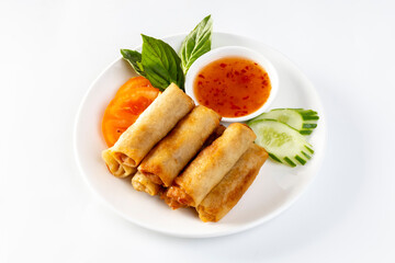 Fried spring rolls, vegetables  with dipping sauce on a white background.