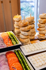 stacks of assorted bagels on wooden sticks and platters of cream cheese, tomatoes, cucumbers and onions at fancy bar mitzvah brunch