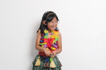 5 year old Latina brunette girl with glasses and Hawaiian skirt enjoys dancing and does Hawaii dance steps very happy and excited