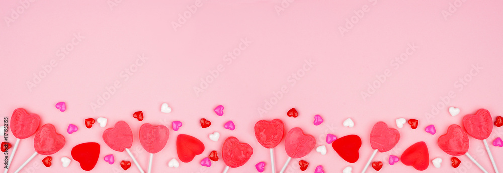Poster valentines day bottom border of candy hearts and lollipops. top down view on a pink banner backgroun