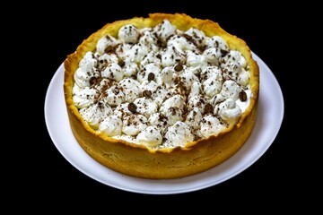 Traditional banoffee cake with banana and caramel sauce filling sprinkled with grated dark chocolate and coffee . English traditional pie