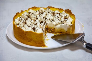 Traditional banoffee cake with banana and caramel sauce filling sprinkled with grated dark chocolate and coffee . English traditional pie