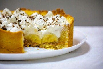 Traditional banoffee cake with banana and caramel sauce filling sprinkled with grated dark chocolate and coffee . English traditional pie