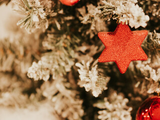 Christmas tree decorations on branches of Christmas tree. Decorations in form of red balls and hexagonal star on decorative Christmas tree. Celebrating New Year. December 31, 2024 - Pula, Croatia