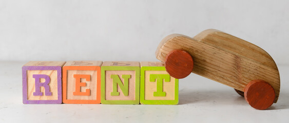 Word RENT with wooden car on white background