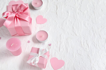 Pink gift boxes, paper hearts and candles on white grunge background. Valentine's Day celebration