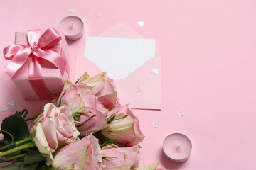 Envelope with blank greeting card, gift box and bouquet of roses on pink background. Valentine's Day celebration