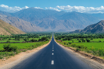 Fototapeta premium Long road winding through lush green valley, surrounded by rolling hills under clear blue sky.