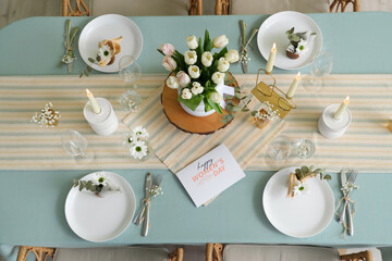 Dining table with setting, tulips and greeting card for International Women's Day celebration