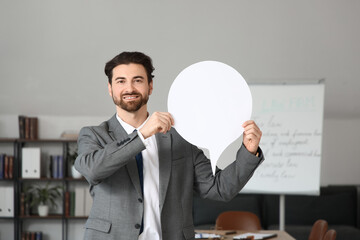 Young businessman with blank speech bubble in office