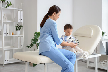 Female pediatrician and cute little boy with molecular model sitting on couch in clinic