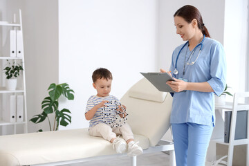 Female pediatrician and cute little boy with molecular model sitting on couch in clinic