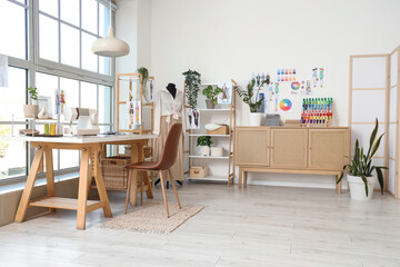 Interior of light atelier with tailor's workplace, mannequin and shelf units