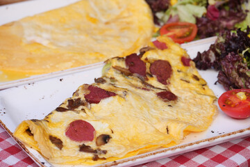 A delicious and hearty omelette featuring sausage alongside a fresh salad