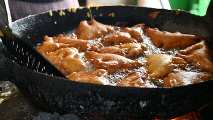 Bread pakora is being fried in hot oil. It is made by stuffing the bread with potatoes and dipping it in the batter of chickpea flour and then frying it. popular snack of India. Indian street food. 

