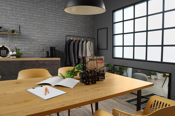 Stand with magazines on table in clothing store office