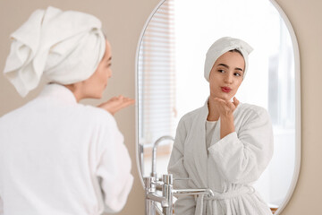Obraz premium Young woman blowing kiss near mirror after shower at home