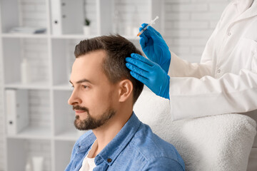 Handsome man receiving injection for hair growth in clinic, closeup