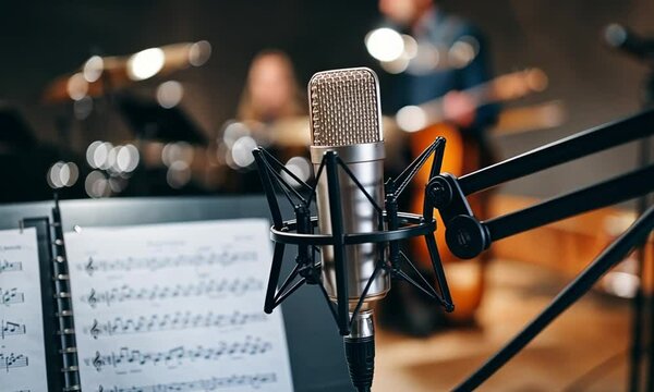 A condenser mic on a boom arm and a blurred sheet of music in the background.