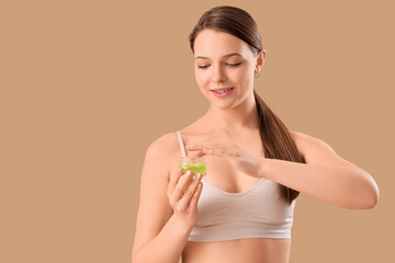 Young woman with dental braces and jar of scrub on beige background