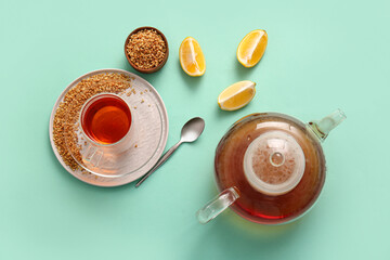 Glass cup and teapot of hot buckwheat tea with lemon on turquoise background